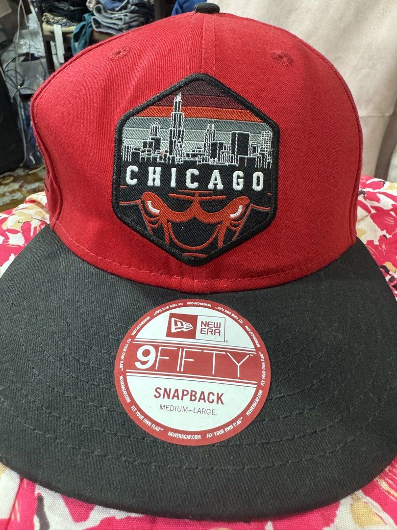 New Era Chicago Bulls 9FIFTY Snapback Cap (Category: Caps & Hats) located in Manila. Submitted by wildbear.e10374 (Listing ID 1468189341, Image 1). Description: - Brand: New Era Hardwood Classics - Team: Chicago Bulls Snapback Cap - Color: Red crown with black flat brim - Design: Detailed skyline patch on front, Windy City lettering, and side bull embroidery - Condition: Brand new with original brim sticker intact - Size: Medium-Large.