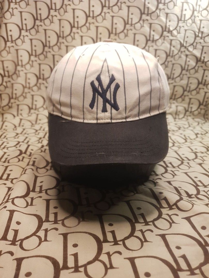 NEW YORK YANKEES PINSTRIPE BASEBALL CAP (Category: Caps & Hats) located in San Fernando. Submitted by _jaximus (Listing ID 1468217358, Image 1). Description: - Brand: New York Yankees - Design: Classic white crown with dark pinstripes and dark brim - Details: Embroidered Yankees logo on the front and matching Yankees script on the adjustable back strap - Condition: Pre-loved, with visible rusting on the metal top button and a small yellowish stai