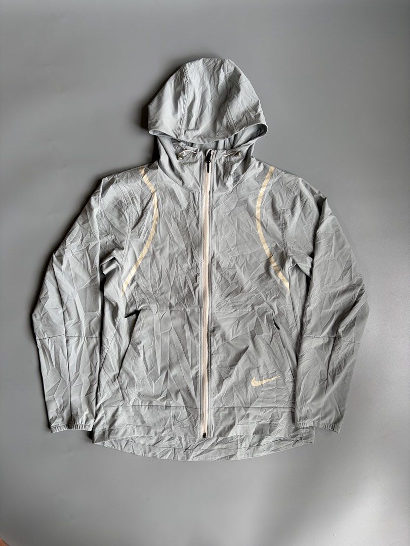 Nike Future Motion V1 Hooded Jacket Grey Size M (Category: Coats, Jackets and Outerwear) located in Kibawe. Submitted by jeloots (Listing ID 1468123280, Image 1). Description: Nike Future Motion V1 zip-up hooded jacket in grey. Size M, made from 85 percent polyester and 15 percent spandex. Full front zipper, side zip pockets, adjustable hood drawcords. Contrast piping details along the front chest. Large Nike graphic printed vertically on the bac