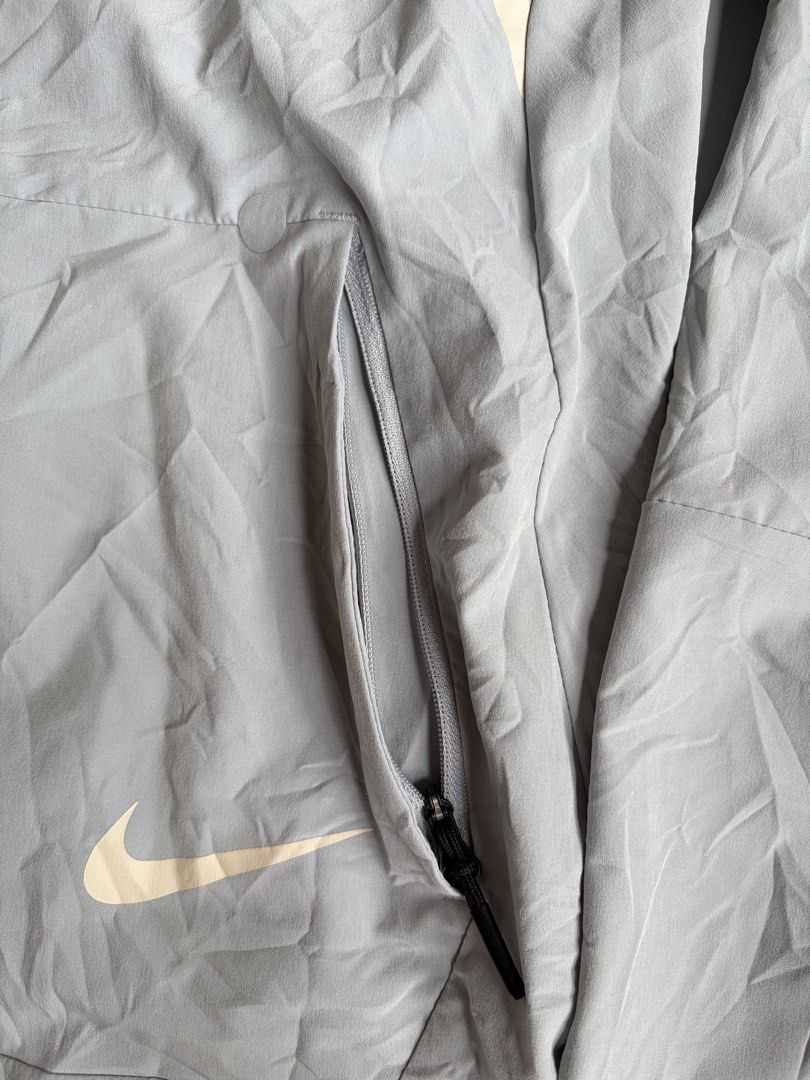 Nike Future Motion V1 Hooded Jacket Grey Size M (Category: Coats, Jackets and Outerwear) located in Kibawe. Submitted by jeloots (Listing ID 1468123280, Image 2). Description: Nike Future Motion V1 zip-up hooded jacket in grey. Size M, made from 85 percent polyester and 15 percent spandex. Full front zipper, side zip pockets, adjustable hood drawcords. Contrast piping details along the front chest. Large Nike graphic printed vertically on the bac