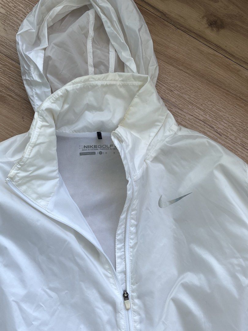 Nike Golf White Hooded Windbreaker Jacket Medium (Category: Coats, Jackets and Outerwear) located in Paranaque City. Submitted by PrelovedClosetetc (Listing ID 1468065401, Image 2). Description: - Brand: Nike Golf - Item: Hooded windbreaker / jacket - Color: White - Features: Full zip front, zippered side pockets, lightweight material - Condition: Good overall with smooth zippers and no rips/tears; has slight yellow discoloration around the insid