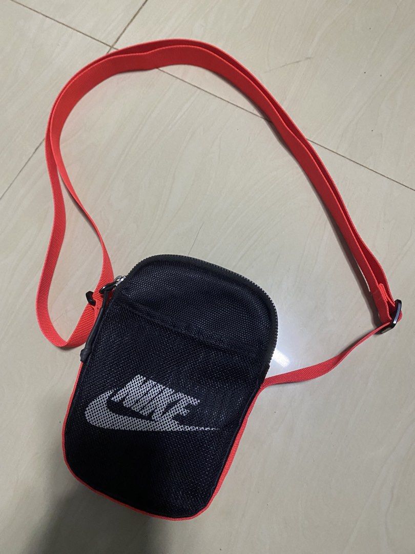 Nike Heritage Cross-Body bag (Category: Sling Bags) located in Manila. Submitted by callejage69430 (Listing ID 1468232668, Image 1). Description: Nike Heritage Cross-Body Bag (Small, 1L) in black with a bright red/neon orange strap.