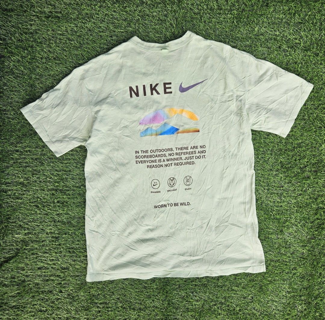 Nike Premium Essentials TShirt (Category: Tshirts & Polo Shirts ) located in Las Pinas. Submitted by rcp123 (Listing ID 1468144009, Image 2). Description: - Brand/Model: Nike T-Shirt - Color: Light green - Size: Men's Medium - Design: Small Nike logo on chest; colorful outdoor mountain graphic, icon stamps ('Enhance', 'Enchant', 'Enjoy'), and inspirational text on the back - Detail: 'Worn to be wild' text near the hem, classic ribbed collar - Con