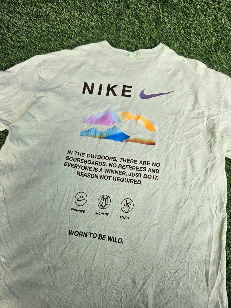Nike Premium Essentials TShirt (Category: Tshirts & Polo Shirts ) located in Las Pinas. Submitted by rcp123 (Listing ID 1468144009, Image 3). Description: - Brand/Model: Nike T-Shirt - Color: Light green - Size: Men's Medium - Design: Small Nike logo on chest; colorful outdoor mountain graphic, icon stamps ('Enhance', 'Enchant', 'Enjoy'), and inspirational text on the back - Detail: 'Worn to be wild' text near the hem, classic ribbed collar - Con