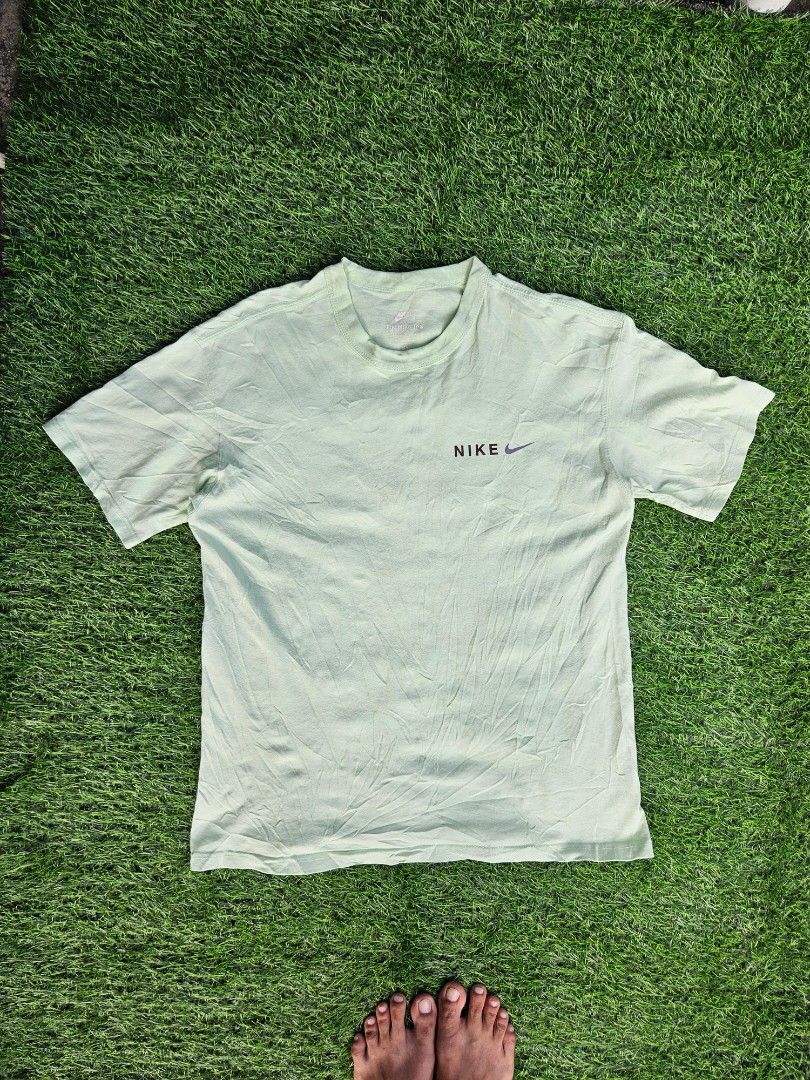 Nike Premium Essentials TShirt (Category: Tshirts & Polo Shirts ) located in Las Pinas. Submitted by rcp123 (Listing ID 1468144009, Image 1). Description: - Brand/Model: Nike T-Shirt - Color: Light green - Size: Men's Medium - Design: Small Nike logo on chest; colorful outdoor mountain graphic, icon stamps ('Enhance', 'Enchant', 'Enjoy'), and inspirational text on the back - Detail: 'Worn to be wild' text near the hem, classic ribbed collar - Con