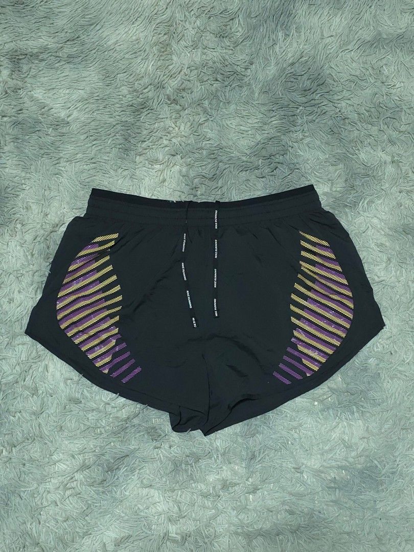 Nike Running Shorts Black With Purple Yellow Pattern (Category: Activewear) located in Abulug. Submitted by humanwhosellthings (Listing ID 1468184726, Image 1). Description: - Brand: Nike ✅Excellent Condition ✅Issue: none ▫️Waist Size: 30-38 ▫️Length: 12 - Color: Black with yellow and purple striped graphic pattern - Fit: Elastic waistband with branded drawstrings - Details: Small reflective swoosh logo on the front leg - Storage: Handy zipped po
