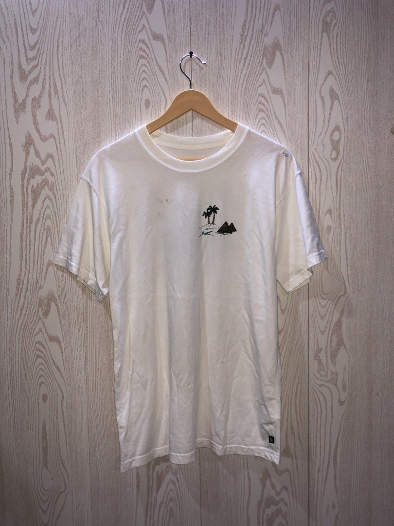 Nike Sphinx Pyramids Graphic T-Shirt White Size M (Category: Tshirts & Polo Shirts ) located in Magsaysay. Submitted by ryns_thrifting (Listing ID 1468165192, Image 1). Description: - Brand: Nike - Style/Model Code: CU0297-100 - Size: Medium - Color: White - Fit: Standard crew neck with short sleeves - Design: Small palm trees and pyramids on the front chest; large Sphinx wearing sneakers on a skateboard graphic on the back with Nike branding - T