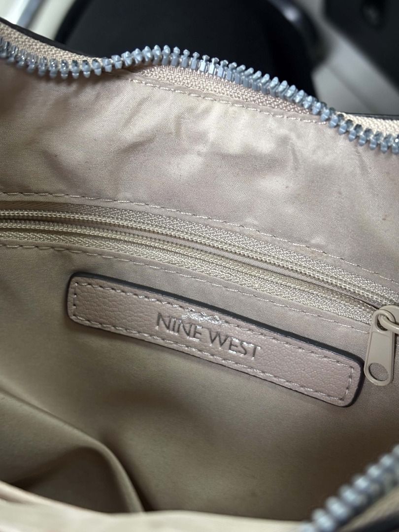 Nine West Beige Shoulder Bag (Category: Shoulder Bags) located in Cebu City. Submitted by re-amoreph_2014 (Listing ID 1468257353, Image 2). Description: - Brand: Nine West - Color: Classic beige with sleek curved design - Hardware: Silver-tone with metallic front logo - Closure: Secure zip closure with single top handle - Interior: Light fabric lining, zippered pocket, and official logo patch - Condition: Brand new with tag attached.