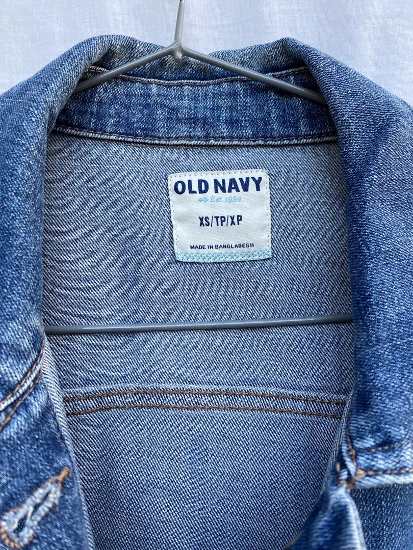 Old Navy Blue Denim Jacket XS (Category: Coats, Jackets and Outerwear) located in Baguio. Submitted by royalriver17 (Listing ID 1468222348, Image 3). Description: - Brand: Old Navy - Size: XS (Made in Bangladesh) - Color/Wash: Classic medium blue with slight fading - Style: Traditional trucker jacket - Details: Front button closure, chest flap pockets, side welt pockets, and tan contrast stitching - Condition: Sturdy denim with a broken-in look.