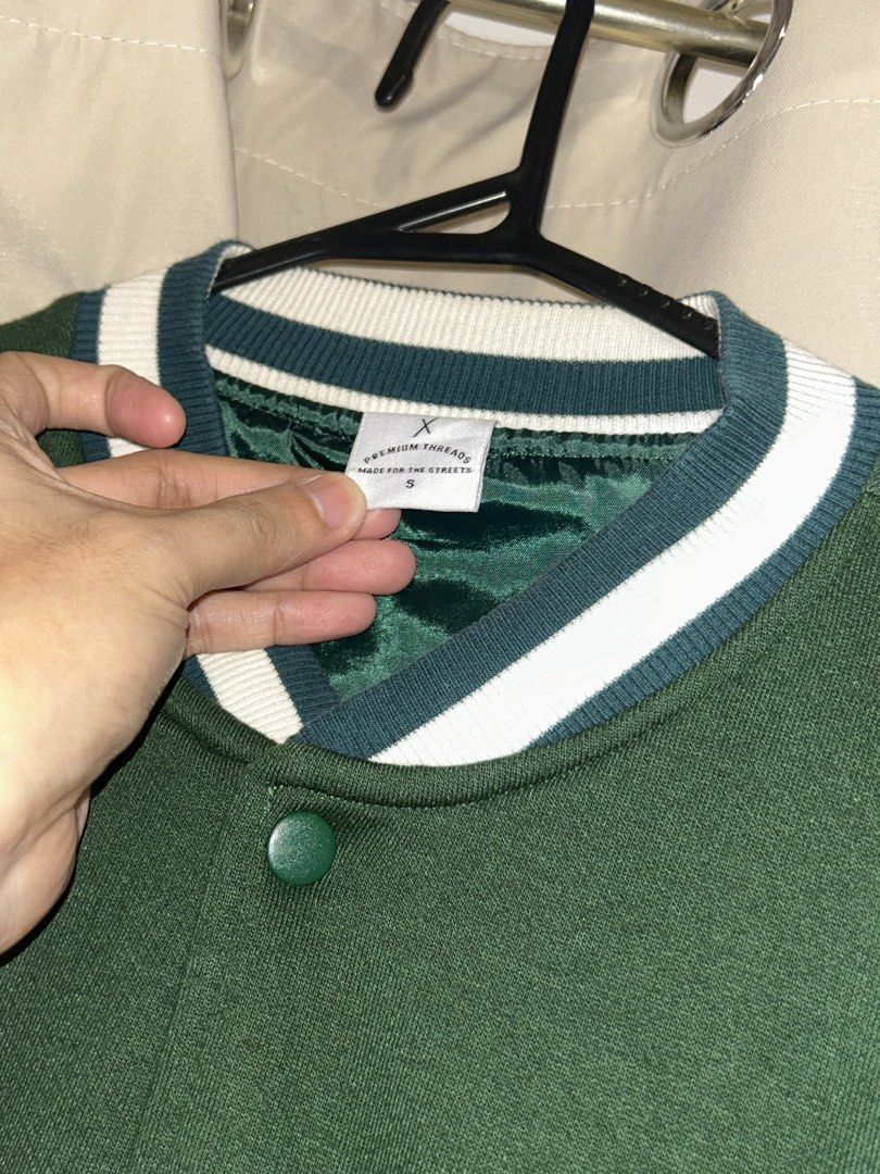 Oxygen Varsity Jacket Green Size S (Category: Coats, Jackets and Outerwear) located in Dasmarinas. Submitted by brandedstuff.est2022 (Listing ID 1468166673, Image 2). Description: - Brand/Model: Oxygen Premium Threads - Size: S - Color: Deep green - Closure: Button-up front with snap buttons - Details: Striped ribbed collar, cuffs, and hem - Lining: Green satin inside - Pockets: Two functional front pockets - Branding: Small debossed logo on the 