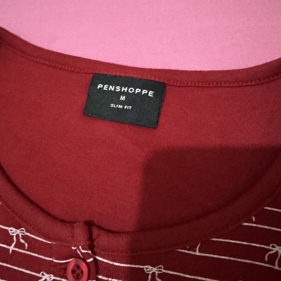 Penshoppe Slim Fit Maroon Top (Category: Shirts) located in San Fernando. Submitted by declotter (Listing ID 1468088834, Image 3). Description: - Brand: Penshoppe - Size: M - Color: Maroon red with white stripes and tiny bow print - Fit: Slim fit with scoop neckline and full front button placket - Style: Cute coquette vibe, perfect everyday basic - Condition: Excellent, no damage or flaws found.