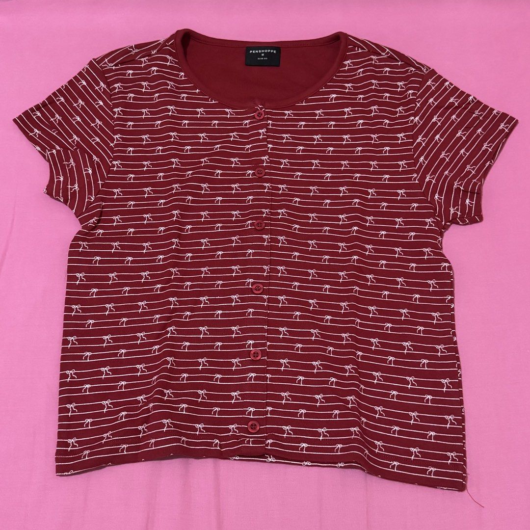 Penshoppe Slim Fit Maroon Top (Category: Shirts) located in San Fernando. Submitted by declotter (Listing ID 1468088834, Image 1). Description: - Brand: Penshoppe - Size: M - Color: Maroon red with white stripes and tiny bow print - Fit: Slim fit with scoop neckline and full front button placket - Style: Cute coquette vibe, perfect everyday basic - Condition: Excellent, no damage or flaws found.