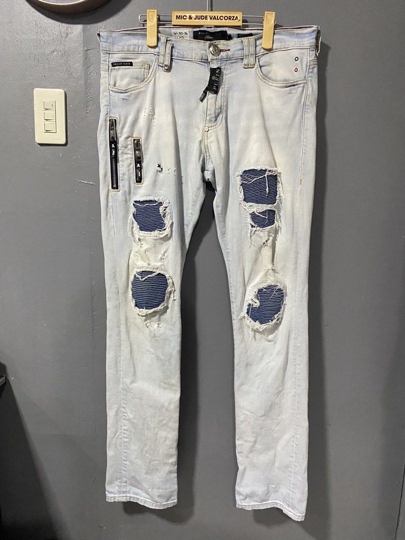 Philipp Plein Biker Distressed Light Wash Jeans (Category: Jeans) located in Tanay. Submitted by judevalcorza (Listing ID 1468224507, Image 1). Description: - Brand: Authentic Philipp Plein Biker ice Cube - Style: Biker jeans with heavy distressing and ripped knees - Details: Striped blue patches underneath rips, multiple zip accents, and black woven pull tabs - Hardware: Branded hardware, skull zip pulls on front pockets, and hexagonal logo plat