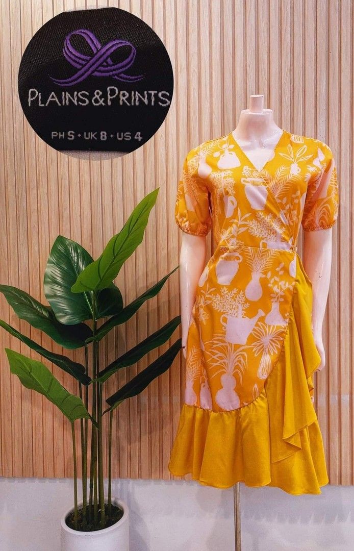 Plains & Prints Yellow Wrap Dress (Category: Dresses) located in Angeles City. Submitted by leichen57360 (Listing ID 1468104079, Image 2). Description: - Brand: Plains & Prints - Color: Yellow with white botanical/vase print - Style: Wrap dress with short sleeves, V-neckline, tie waist sash, and ruffled hem - Size: PH S, UK 8, US 4 - Condition: Pre-loved, well-maintained.
