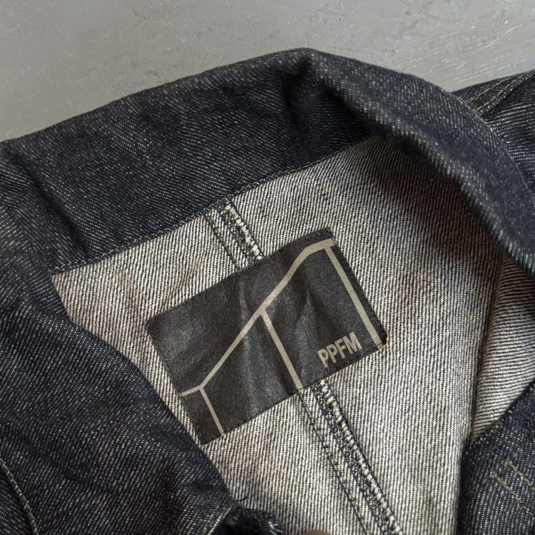 PPFM Dark Denim Chore Jacket Workwear Outerwear (Category: Coats, Jackets and Outerwear) located in Legazpi City. Submitted by keantuttt (Listing ID 1468134687, Image 3). Description: - Brand: PPFM - Style: Dark denim work jacket - Size: Tag reads F - Closure: Button front - Pockets: Chest pocket, two lower slanted pockets, and multiple interior pockets - Details: Contrasting white stitching and branded woven labels - Material: Heavyweight, rigid