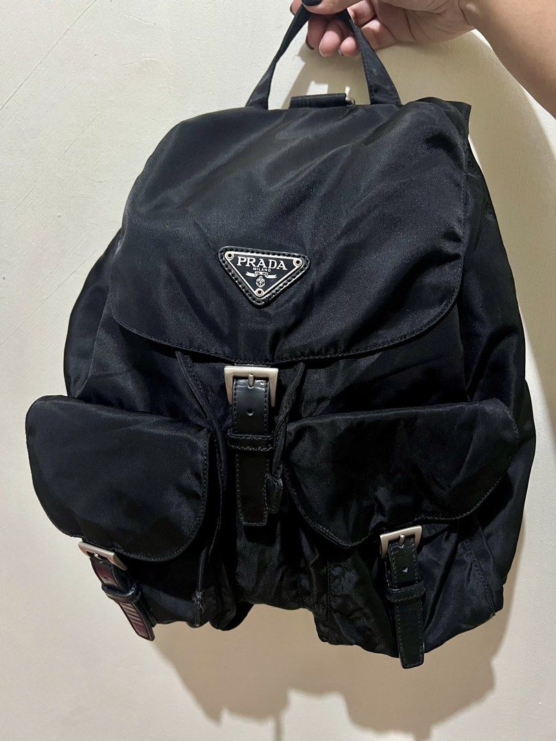 Authentic Prada Black Nylon Backpack (Category: Luxury Bags & Wallets) located in Dagupan City. Submitted by casadebayongph (Listing ID 1468221405, Image 2). Description: Black nylon Prada backpack. Classic triangle logo badge on the front flap. Drawstring closure with buckled front straps. Two front pockets with buckled flaps. Adjustable black webbed shoulder straps and top handle. Silver-tone hardware throughout. Clean interior and exterior. Cu