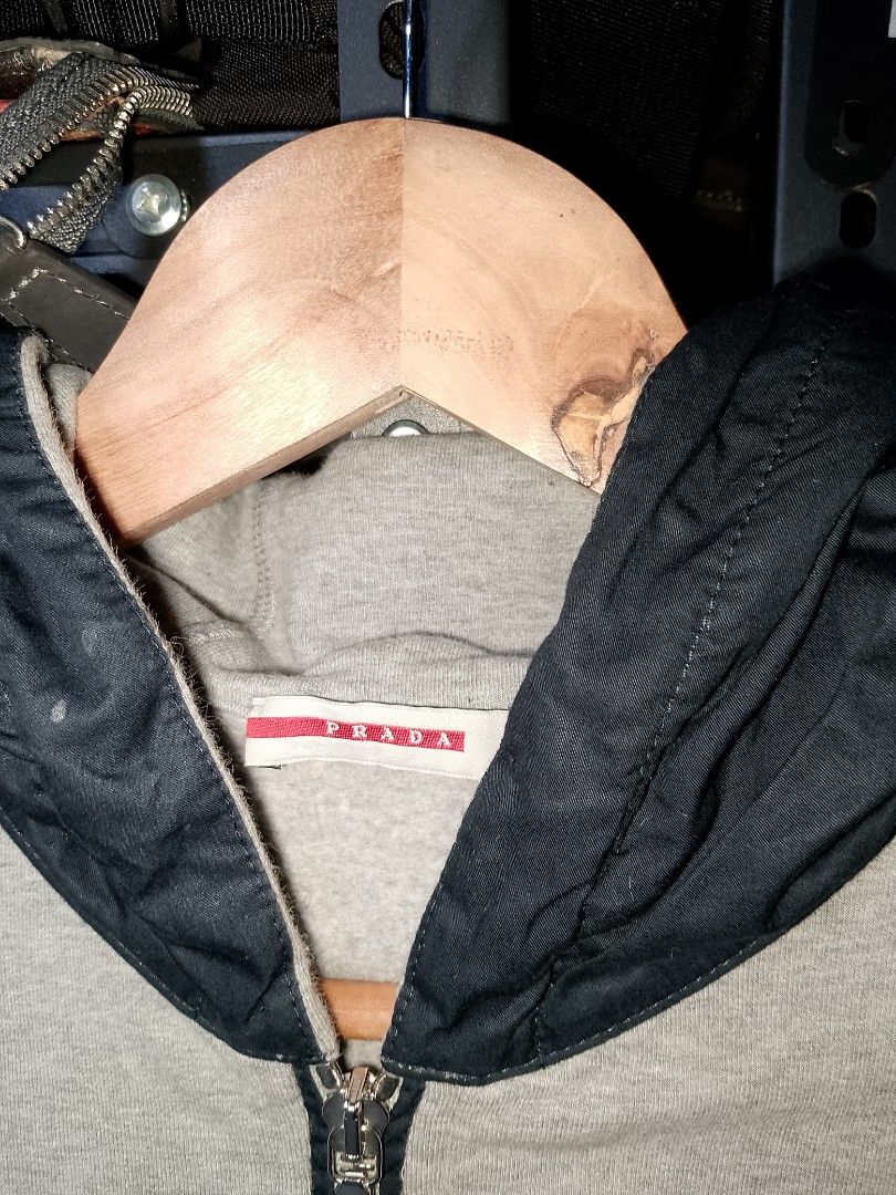 Prada Grey Hoodie Zip Jacket (Category: Coats, Jackets and Outerwear) located in Manila. Submitted by mjthrifted_second (Listing ID 1468091959, Image 2). Description: - Brand: Prada -Dimes: 17/21 - Color: Grey with contrasting black hood - Material: Premium cotton - Features: Full front zip closure, front zipper pockets, engraved Prada Milano hardware - Branding: Red Prada rubber logo patch on the left chest - Details: Ribbed cuffs and hem for a 