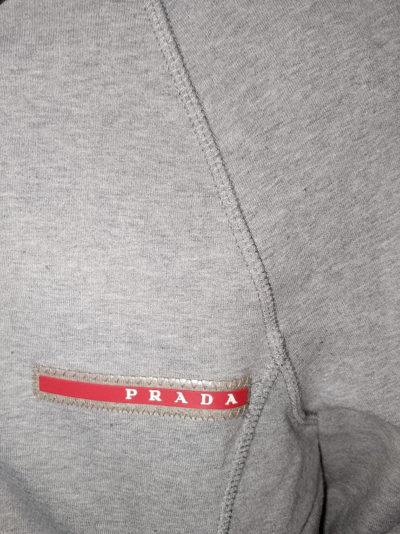 Prada Grey Hoodie Zip Jacket (Category: Coats, Jackets and Outerwear) located in Manila. Submitted by mjthrifted_second (Listing ID 1468091959, Image 3). Description: - Brand: Prada -Dimes: 17/21 - Color: Grey with contrasting black hood - Material: Premium cotton - Features: Full front zip closure, front zipper pockets, engraved Prada Milano hardware - Branding: Red Prada rubber logo patch on the left chest - Details: Ribbed cuffs and hem for a 