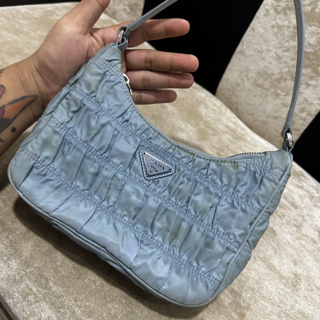 Prada Ruched Nylon Shoulder Bag Light Blue (Category: Luxury Bags & Wallets) located in Quezon City. Submitted by retroboominwantsummoh (Listing ID 1468255469, Image 2). Description: - Prada shoulder bag in gorgeous light blue ruched nylon - Shiny silver-tone hardware with smooth Lampo zipper closure - Classic Prada metal triangle logo on the front - Interior lined with signature Prada logo fabric - Includes Milano metal plaque tag and "Made in I