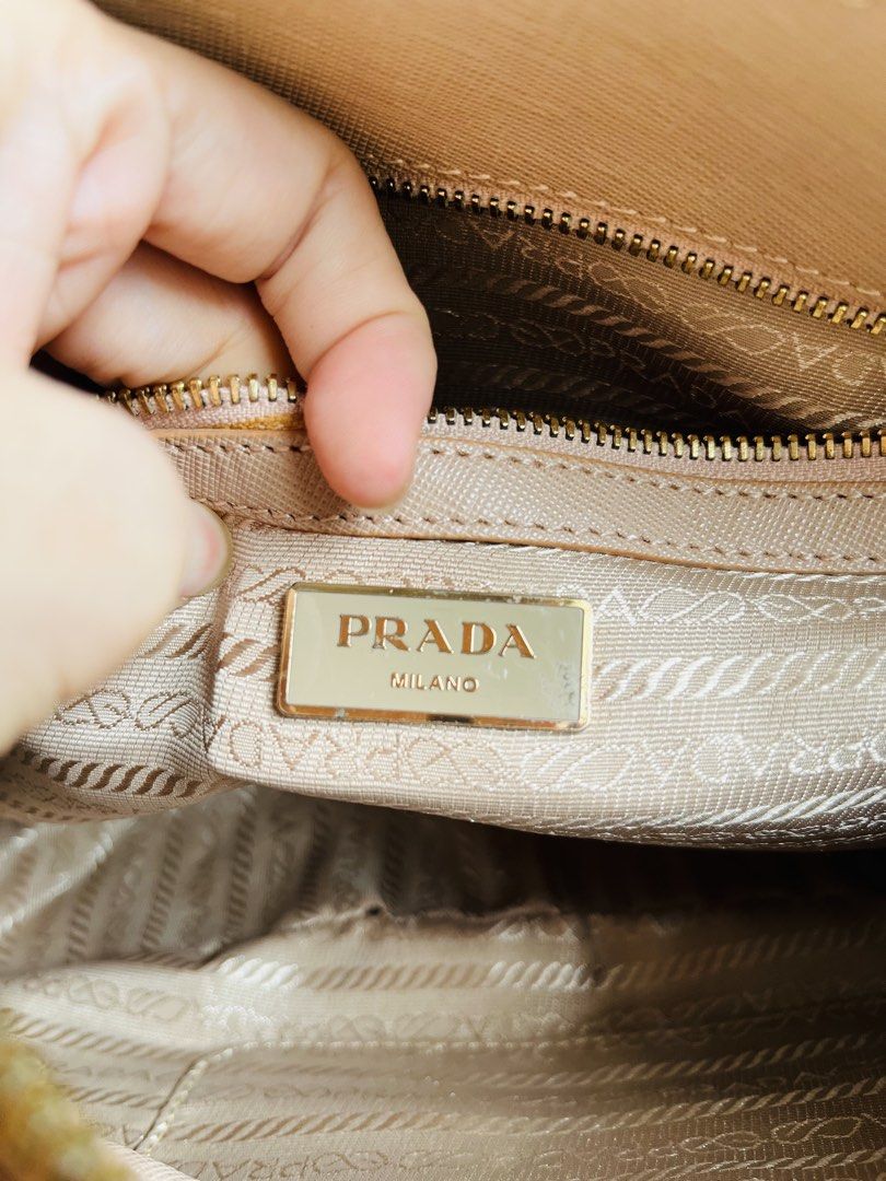 Prada Saffiano Leather Handbag Taupe (Category: Luxury Bags & Wallets) located in Davao. Submitted by goodthingsph_ (Listing ID 1468076513, Image 2). Description: - Material: Saffiano leather in a versatile taupe shade - Hardware: Gold-tone with stylish front buckle details - Handles: Double top handles for easy carrying - Branding: Iconic signature triangle logo plaque on the front - Closure: Secure zip top closure - Interior: Branded fabric lin