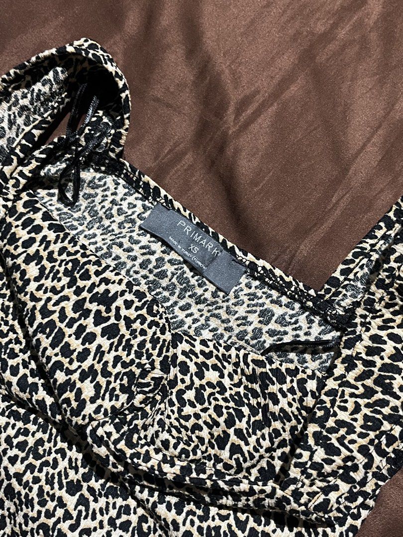 PRIMARK Animal Top Size XS (Category: Sleeveless) located in Manila. Submitted by maaya.rikit (Listing ID 1468104345, Image 3). Description: - Brand: Primark - Size: XS - Pattern: Black and white leopard print - Design: Square neckline, thick straps, and front knot detail - Fit: Cropped length, soft, and stretchy fabric.