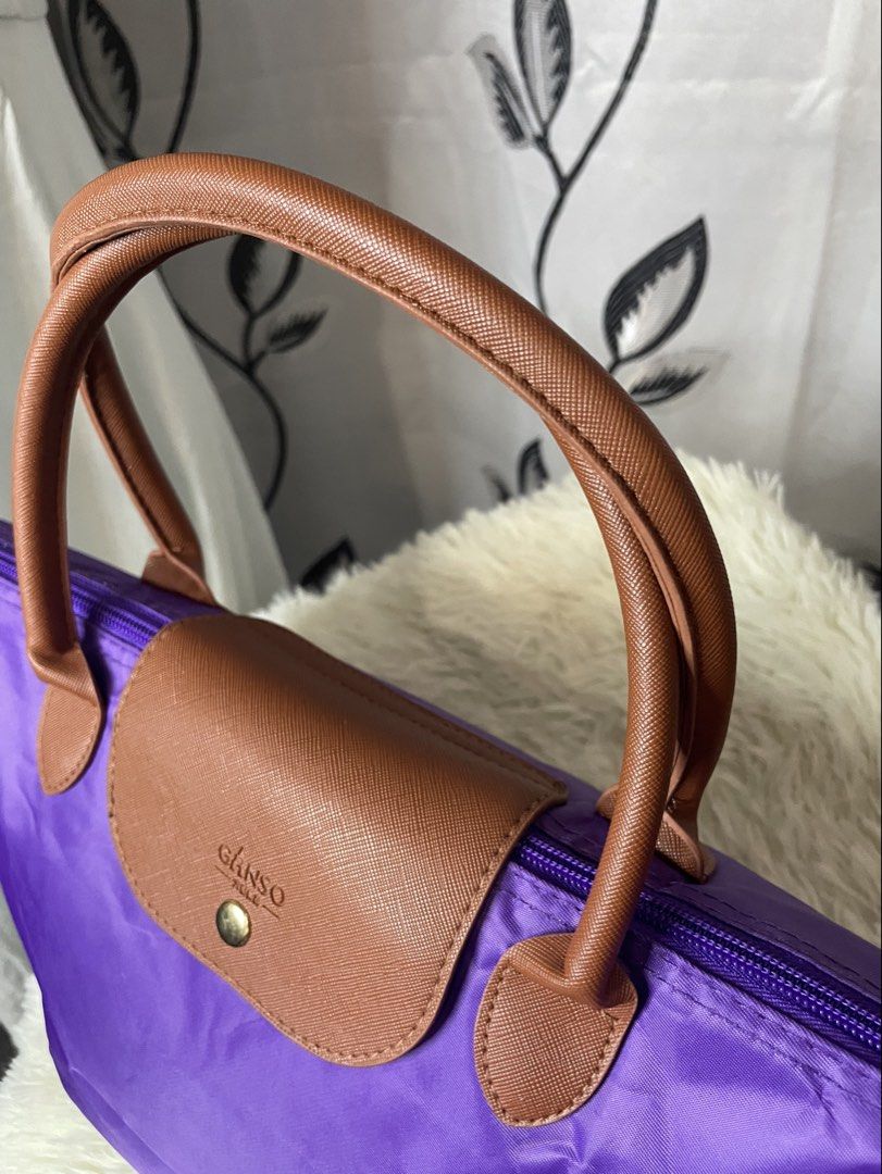 Purple GANSO Tote Bag – Stylish & Spacious (Category: Tote Bags) located in Cabanatuan. Submitted by moraiahraven (Listing ID 1468146537, Image 1). Description: Brand: GANSO Colour: Vibrant purple with brown handles & trim Material: Lightweight nylon body + leather handles & flap Features: • Classic foldable-style tote design • Dual brown top handles • Zip-top closure with branded metal pull • Front flap with gold-tone snap button + embossed GANS