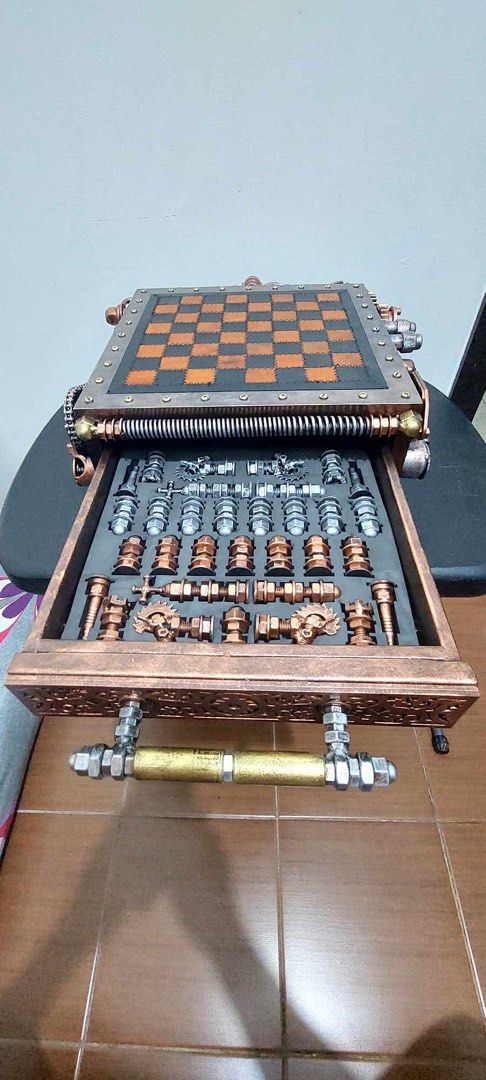 Ram Mallari Steampunk Custom Handmade Chess Set with Storage Drawer (Category: Vintage Collectibles) located in Las Pinas. Submitted by bluemieeeee (Listing ID 1468177546, Image 3). Description: - Custom steampunk chess set with intricate mechanical gears, springs, and textured metal finishes - Leather-look checkered board top with stunning copper-toned accents and distinct hardware - Built-in pull-out storage drawer with custom foam slots to hol