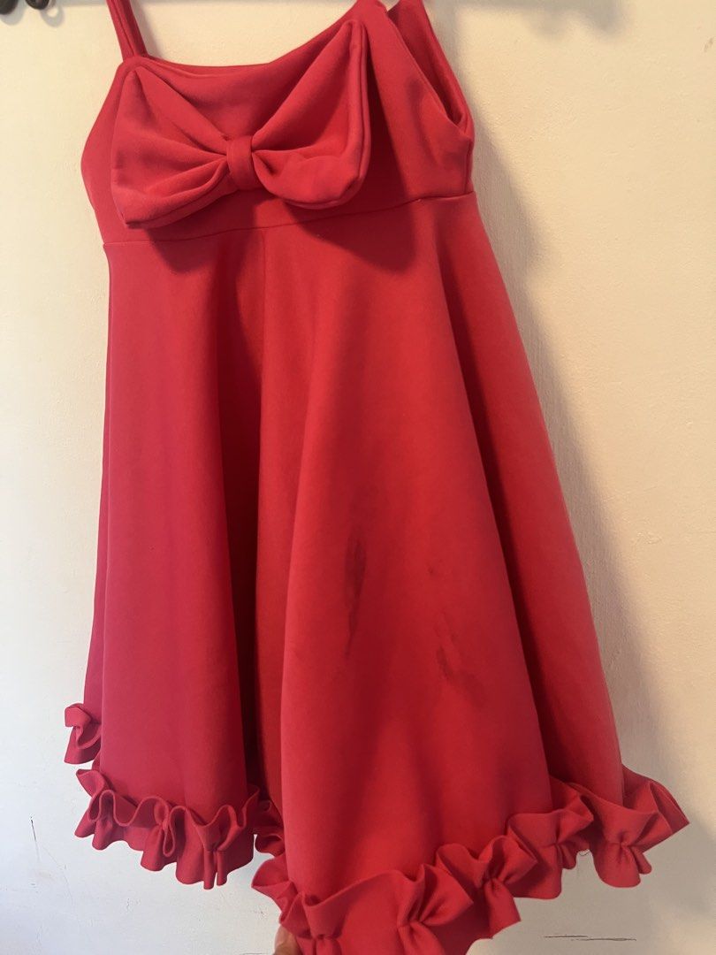 Red Spaghetti Strap Dress with Front Bow and Ruffle Hem (Category: Dresses) located in Manila. Submitted by yliahdreye52249 (Listing ID 1468098132, Image 2). Description: - Color: Bright pink - Style: Spaghetti strap dress with a flared skater skirt and thick ruffled hem - Detail: Large structured bow accent on the front bodice - Condition: Pre-loved with visible dark stains on the lower front section (please check the second photo for reference)