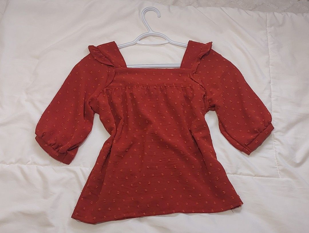 Crissa Swiss Dot Square Neck Blouse with Ruffled by Straps (Category: Blouses) located in Pasig City. Submitted by salazaralona (Listing ID 1468066813, Image 2). Description: - Color: Rusty red with all-over dotted texture - Neckline & Straps: Square neckline with playful ruffled shoulder straps - Sleeves: Half sleeves - Closure: Functional front button closure - Details: Gathered yoke across the chest - Material: Lightweight and breathable - Sty
