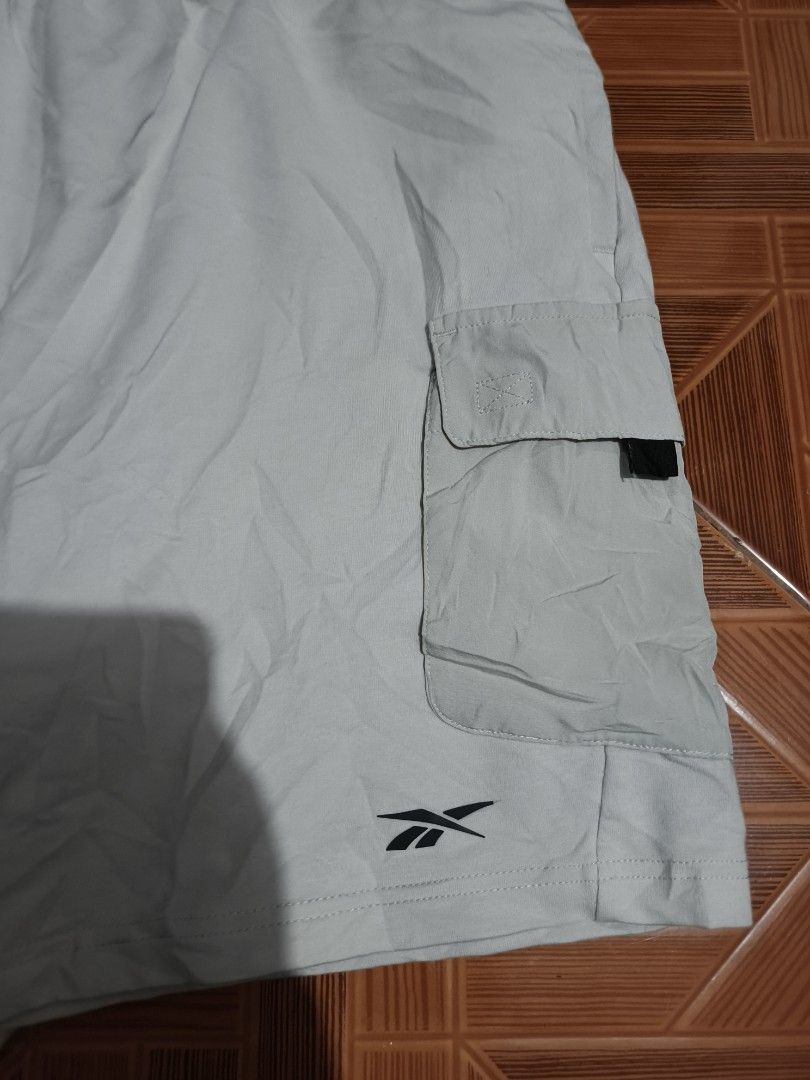 Reebok Cargo Shorts Light Grey Size M (Category: Shorts) located in Manila. Submitted by dyastenthrift (Listing ID 1468163341, Image 2). Description: - Brand: Reebok - Style: Cargo Shorts - Color: Light Grey - Size: Medium - Waistband: Elastic with branded black inner band and adjustable drawstring - Pockets: Large cargo pockets on both legs - Details: Small embroidered logo near the hem - Origin: Made in Cambodia - Condition: Great for casual ev