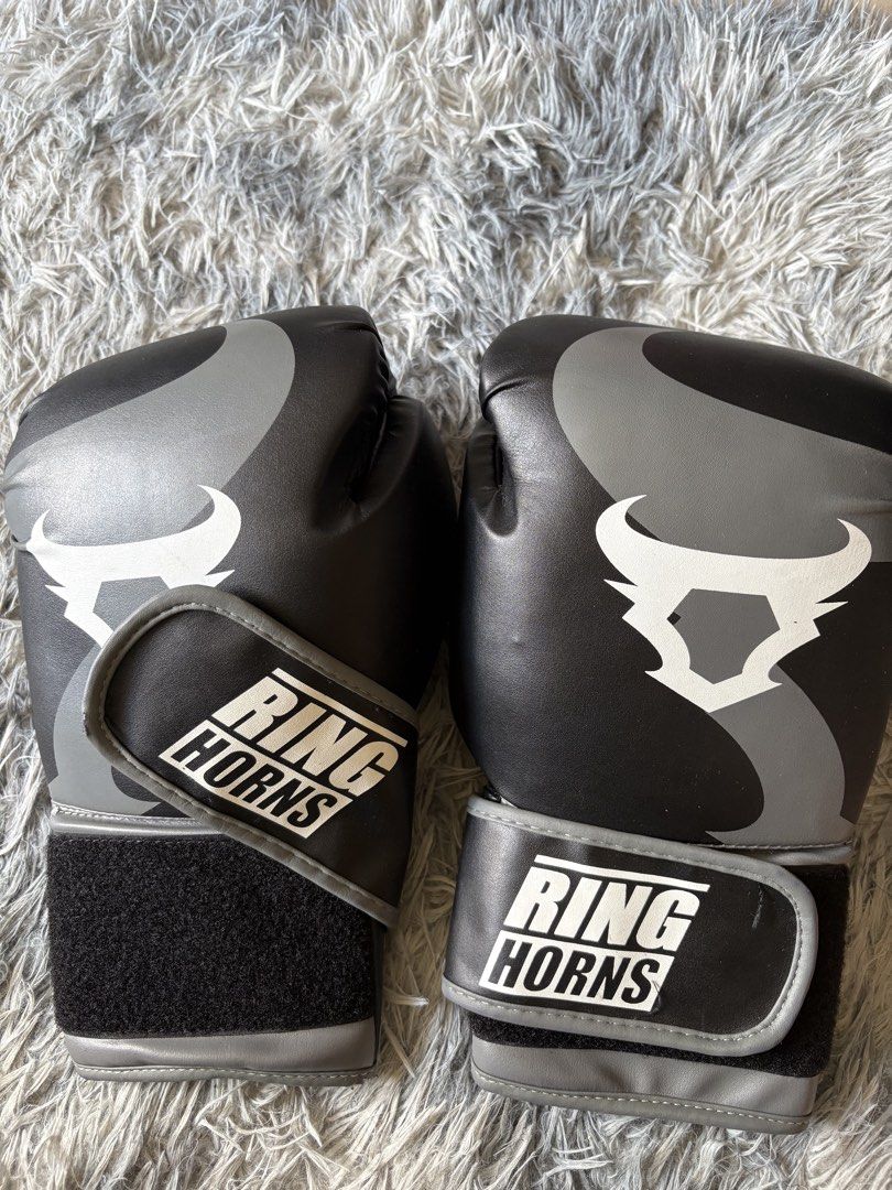 Ring Horns Black and Grey Boxing Gloves (Category: Combat Sports) located in Manila. Submitted by loislane112233 (Listing ID 1468092824, Image 1). Description: - Color: Black and grey - Design: Bold bull logo graphic on the front - Support: Wide velcro wrist strap with branded white text - Protection: Padded construction ideal for training or sparring.