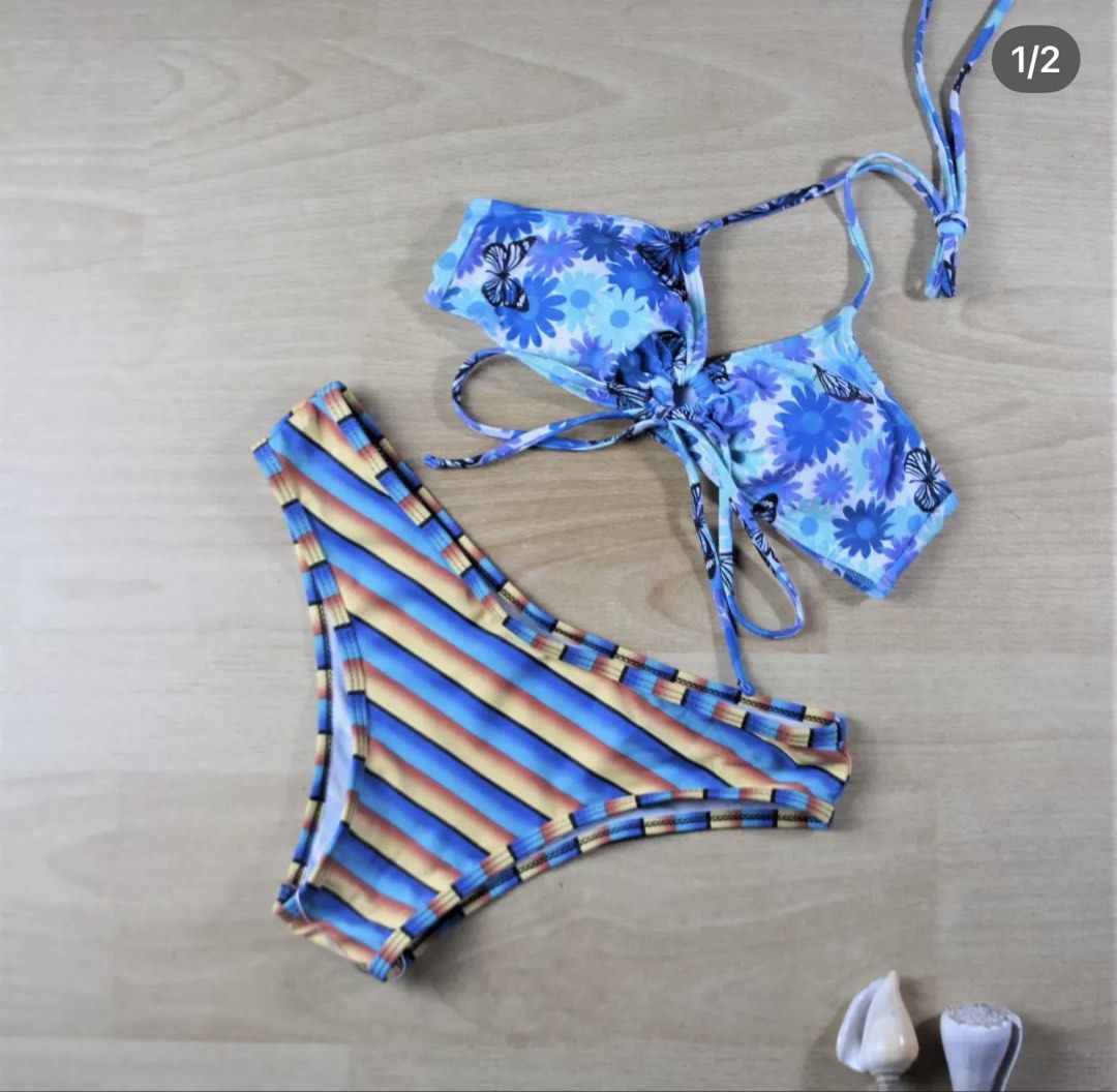 Romwe Blue Floral & Striped Bikini Set Size S (Category: Bikinis & Swimsuits) located in Bulacan. Submitted by peach1025 (Listing ID 1468116820, Image 1). Description: - Brand: Romwe - Type: Two-piece swimsuit - Size: S (tag attached) - Top: Blue butterfly and daisy floral print with adjustable tie straps - Bottoms: Colorful striped pattern in blue, yellow, and orange - Lining: Clean white lining on both pieces - Condition: Great for the beach or