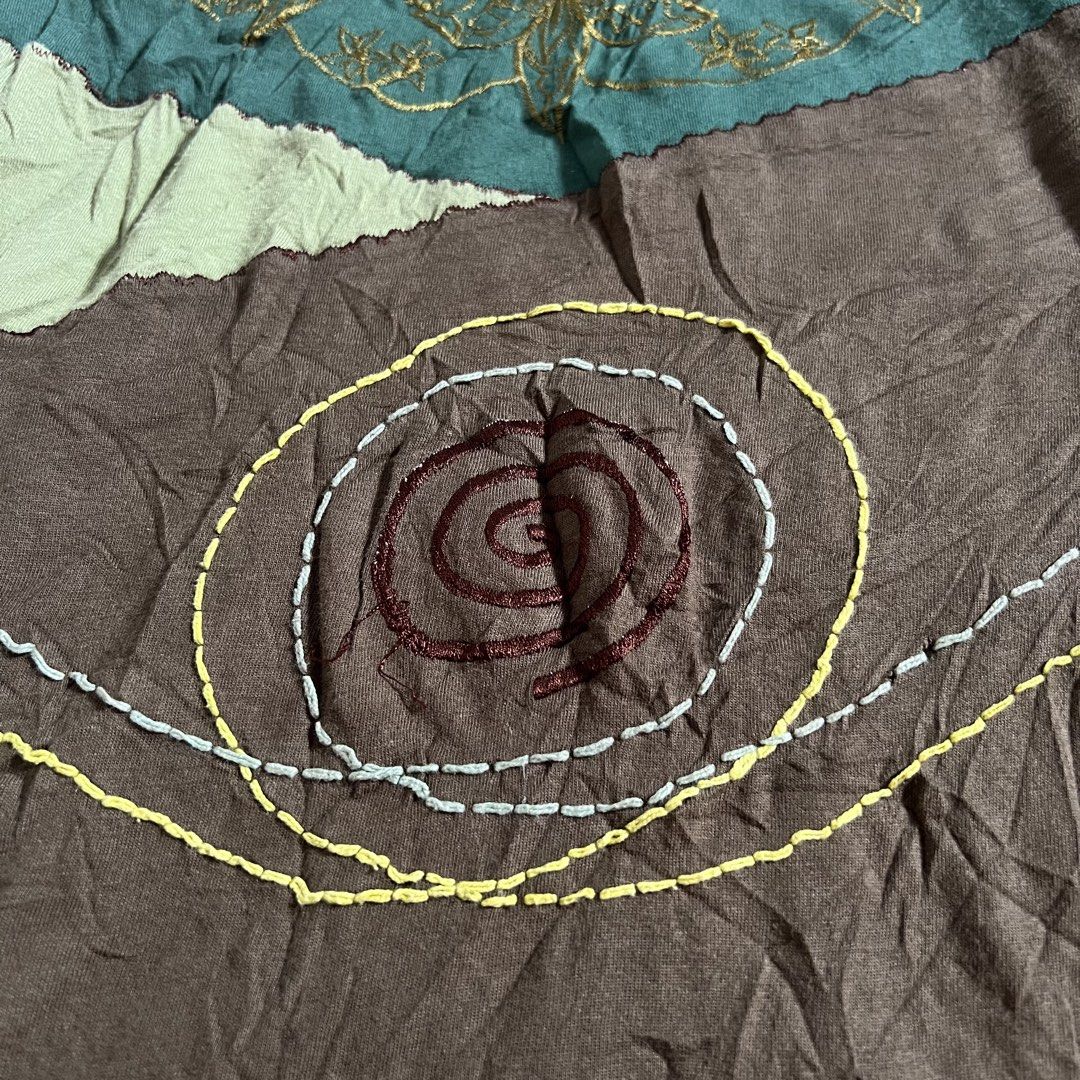 Roxy Lama Patchwork Long Sleeve Top Size L (Category: Longsleeves) located in Manila. Submitted by threadly (Listing ID 1468232349, Image 3). Description: - Brand: Roxy Lama - Size: L (tag attached) - Design: Boho hippie multi-color patchwork (brown, green, maroon, and olive tones) - Neckline: V-neck with green trim - Details: Embroidered leaf accents on the chest and spiral stitching near the hem - Sleeves: Unique printed patterns on sleeves and