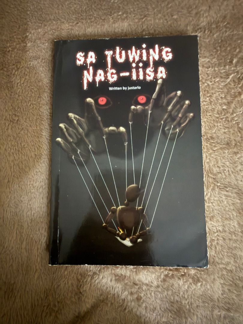 Sa Tuwing Nag-iisa by Justarlo (Category: Storybooks) located in Manila. Submitted by vaultfinds (Listing ID 1468257011, Image 1). Description: Filipino horror novel titled Sa Tuwing Nag-iisa, written by justarlo. Creepy cover design featuring glowing red eyes, shadowy hands, and puppet strings manipulating a small figure. Softcover book in decent shape. Good read for fans of local horror fiction and suspense stories..