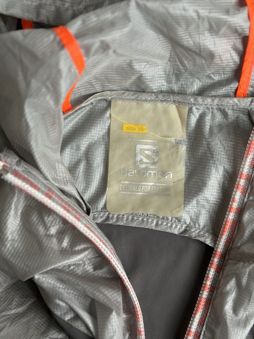 Salomon Native Jacket W (Category: Coats, Jackets and Outerwear) located in Kibawe. Submitted by jeloots (Listing ID 1468085801, Image 2). Description: - Brand: Salomon - Style: Native Jacket W - Color: Silver grey with orange and dark grey panels - Size: 95 (Medium) - Material: Lightweight ripstop - Details: Full zip closure, dual-tone zipper pull, attached hood with orange trim, Salomon branding on chest.