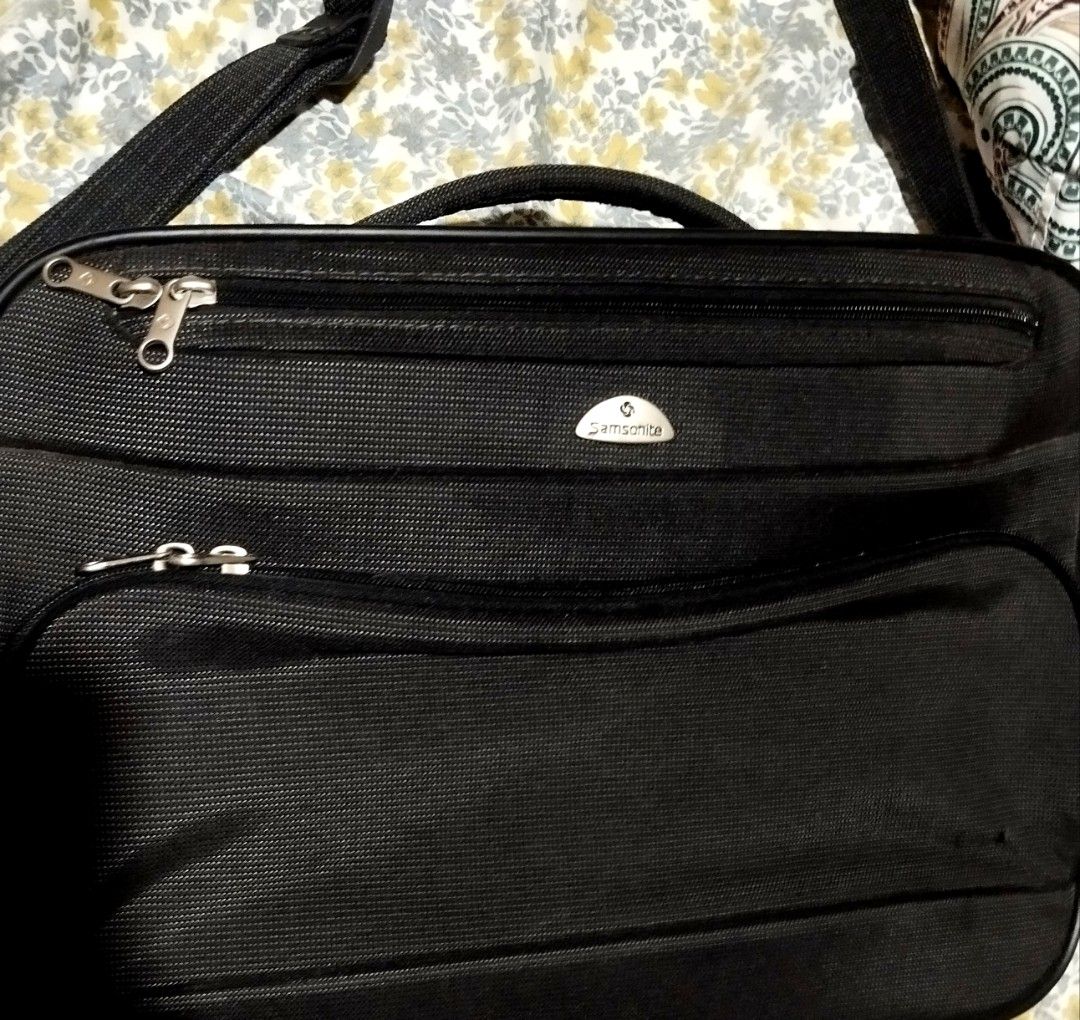 Samsonite Black Laptop Briefcase Shoulder Bag (Category: Briefcases) located in Manila. Submitted by lene48 (Listing ID 1468121033, Image 1). Description: Samsonite business bag in black. Made of durable textured nylon material. Multiple zippered compartments on the front for organizing chargers, documents, and small items. Includes both top grab handles and an adjustable shoulder strap with a padded cushion. Hard protective feet on the bottom pa