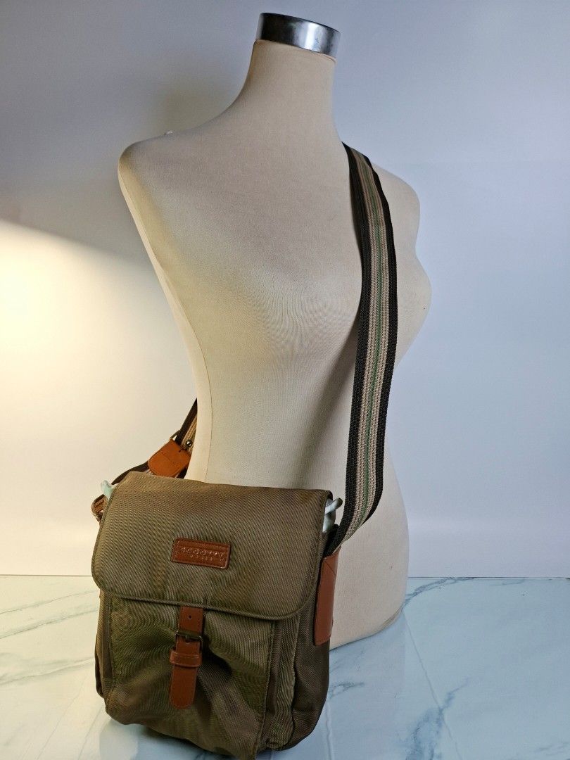 Scooter Brown Nylon Crossbody Bag (Category: Cross-body Bags) located in Pasay City. Submitted by onick_79 (Listing ID 1468251218, Image 2). Description: -Dimensions: L23 x H23 x 12 cm - Color: Brownish-green with brown leather-look accents - Material: Durable nylon - Strap: Adjustable striped strap with buckle detail - Closure: Front flap with strap and metal buckle - Storage: Extra zipper pocket on the back for easy access - Size: Compact and i