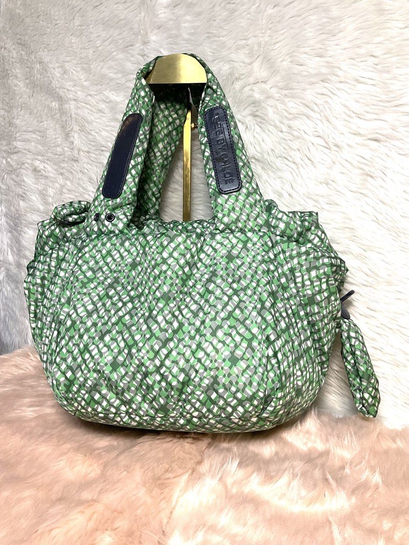 See By Chloe Green Geometric Pattern Tote Bag (Category: Tote Bags) located in La Trinidad. Submitted by naravincollections (Listing ID 1468070774, Image 1). Description: Green geometric pattern handbag from See By Chloe. Puffed nylon body with sturdy top handles. Black fabric lining inside, includes a zippered pocket and brand tag patch. Chunky zip closure with a blue branded pull tab. Clean interior, tag booklet included. Flaws: like new sana i