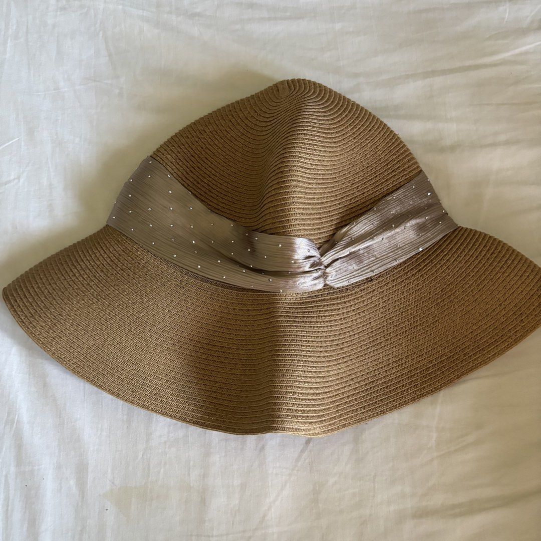 Shein Beige Rafia Sun Hat (Category: Hats & Beanies) located in Binan City. Submitted by myprelovedhaul (Listing ID 1468071798, Image 2). Description: The image shows a tan or beige straw/rafia sun hat featuring a wide brim and a gathered metallic/satin ribbon band adorned with small sparkling or dotted accents.