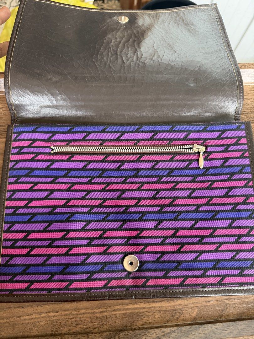 Shiseido Patterned Clutch Bag with Brown Leather Trim (Category: Clutches) located in Digos. Submitted by old_soul. (Listing ID 1468100217, Image 2). Description: - Brand: Shiseido - Type: Clutch Bag - Exterior: Vibrant purple and pink geometric fabric pattern with brown leather trim - Hardware: Elegant gold-tone clasp closure - Interior: Brown fabric lining with a convenient zippered pocket - Closure: Secure magnetic snap closure - Details: Stam