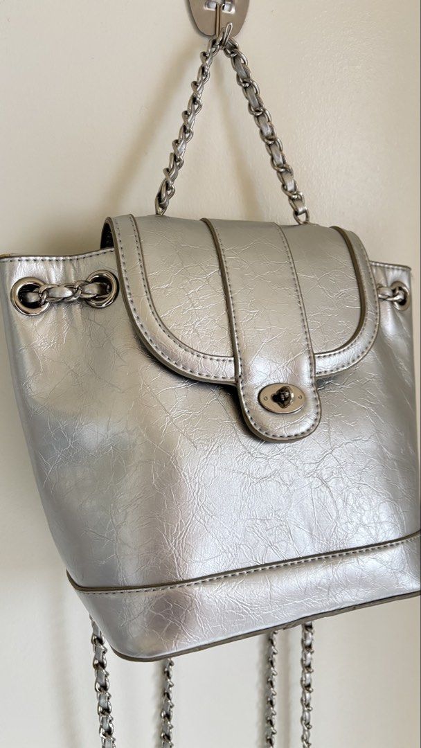 Silver metallic mini backpack with chain straps (Category: Backpacks) located in Baguio. Submitted by zenforest.fd186d (Listing ID 1468224986, Image 3). Description: Silver metallic mini backpack with a crinkled texture. - Twist-lock closure on the front flap. - Chain straps and top handle in silver-tone hardware. Inside is lined with striped fabric and includes a small slip pocket. - Hardware has a few minor scuffs, but overall clean shape..