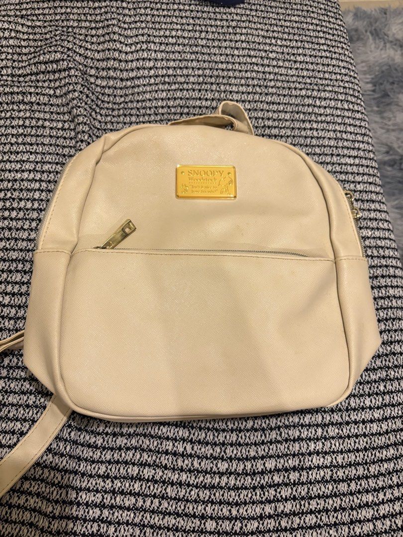 Snoopy Woodstock Cream Mini Backpack (Category: Backpacks) located in Manila. Submitted by loislane112233 (Listing ID 1468187344, Image 1). Description: - Color: Cream faux leather - Design: Snoopy & Woodstock graphics with gold metal quote plaque - Compartments: Front zip pocket & double zip main closure - Straps: Adjustable shoulder straps & top grab handle - Hardware: Gold-tone accents throughout.