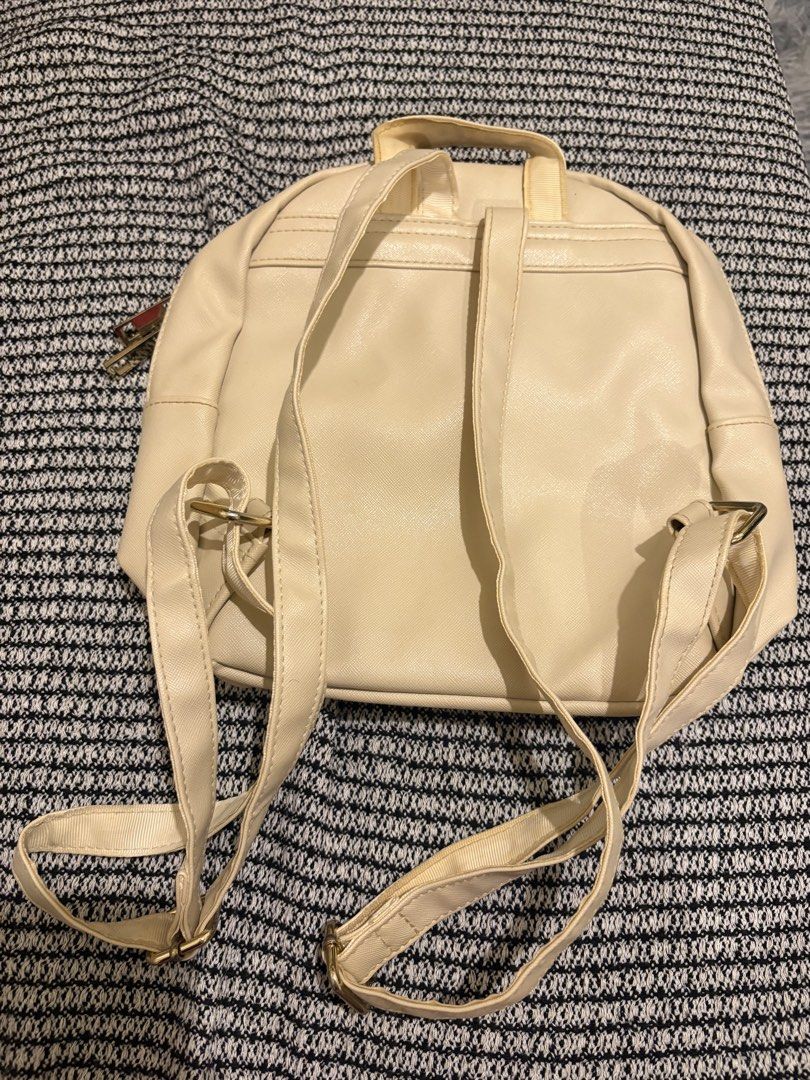 Snoopy Woodstock Cream Mini Backpack (Category: Backpacks) located in Manila. Submitted by loislane112233 (Listing ID 1468187344, Image 3). Description: - Color: Cream faux leather - Design: Snoopy & Woodstock graphics with gold metal quote plaque - Compartments: Front zip pocket & double zip main closure - Straps: Adjustable shoulder straps & top grab handle - Hardware: Gold-tone accents throughout.