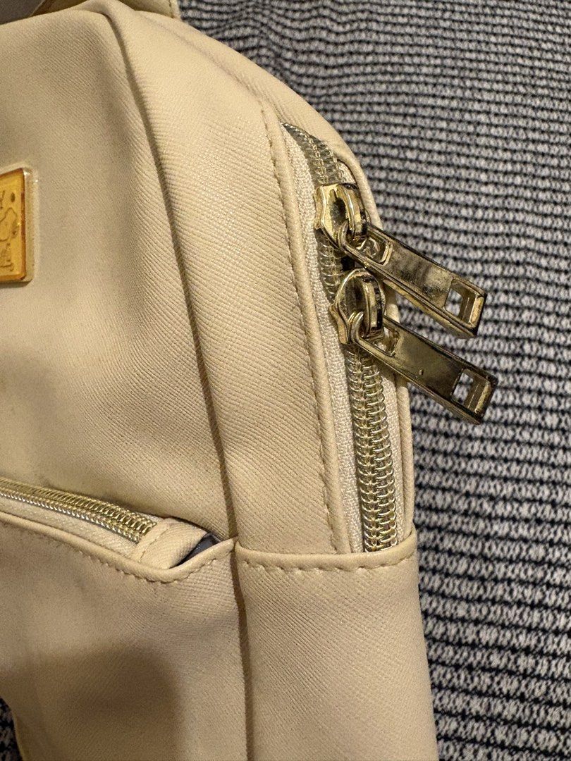 Snoopy Woodstock Cream Mini Backpack (Category: Backpacks) located in Manila. Submitted by loislane112233 (Listing ID 1468187344, Image 2). Description: - Color: Cream faux leather - Design: Snoopy & Woodstock graphics with gold metal quote plaque - Compartments: Front zip pocket & double zip main closure - Straps: Adjustable shoulder straps & top grab handle - Hardware: Gold-tone accents throughout.