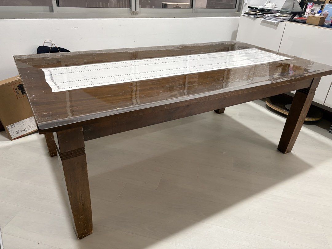 Solid Wooden Dining Table (Category: Tables & Sets) located in Singapore. Submitted by peaceofme (Listing ID 1468217644, Image 2). Description: - Material: Sturdy solid teak wood - Design: Rectangular top with thick legs (minor scuffs near the base from everyday use) - Included: Clear protective plastic cover - Capacity: Comfortably fits 8 chairs -Measurement: 194cm x99cm x74cm(ht) - Versatility: Perfect for meals, homework, and family gatherings