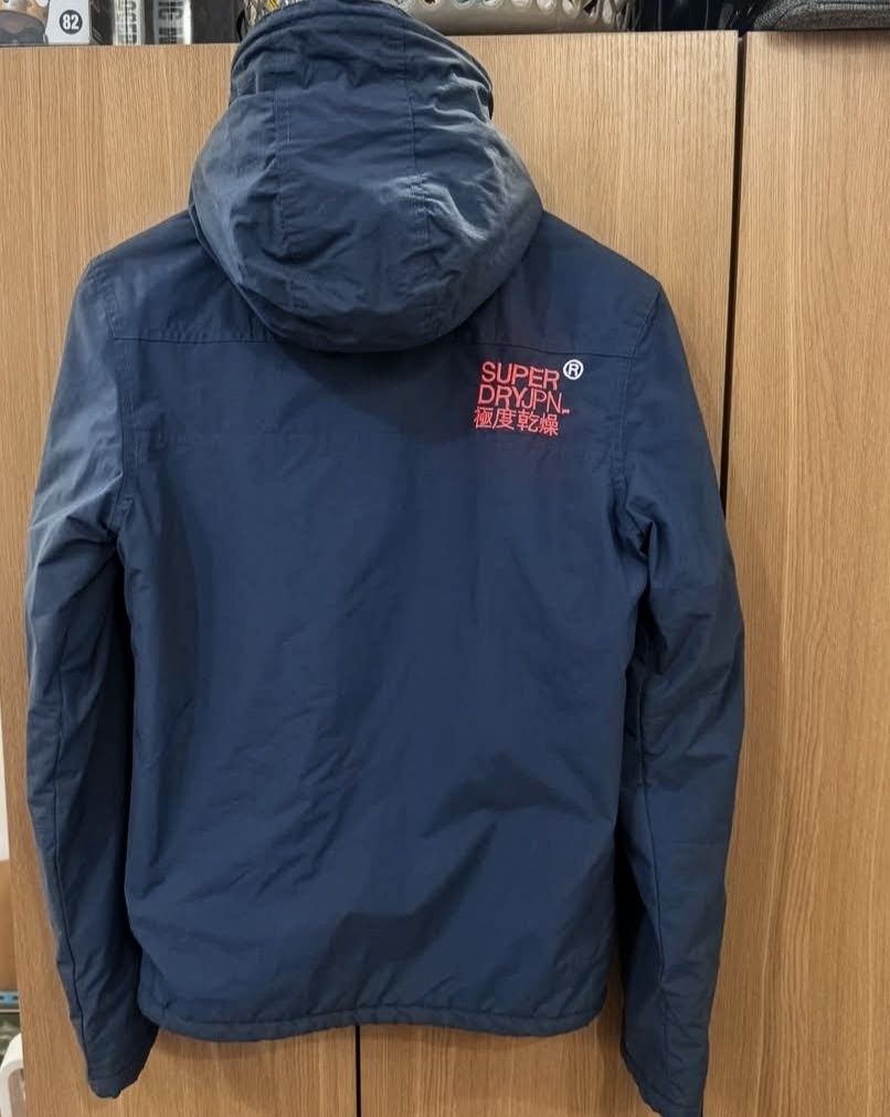 Superdry Original Windhiker Japan Quilted Jacket (Category: Coats, Jackets and Outerwear) located in Manila. Submitted by milamartina123 (Listing ID 1468099896, Image 3). Description: - Brand: Superdry Original Windhiker Japan - Color: Dark navy blue with bright coral pink contrast details - Lining: Quilted fleece for extra warmth - Size: S can fit M - Features: High collar, zip closure, and Japanese text print on hood and upper sleeve - Conditio