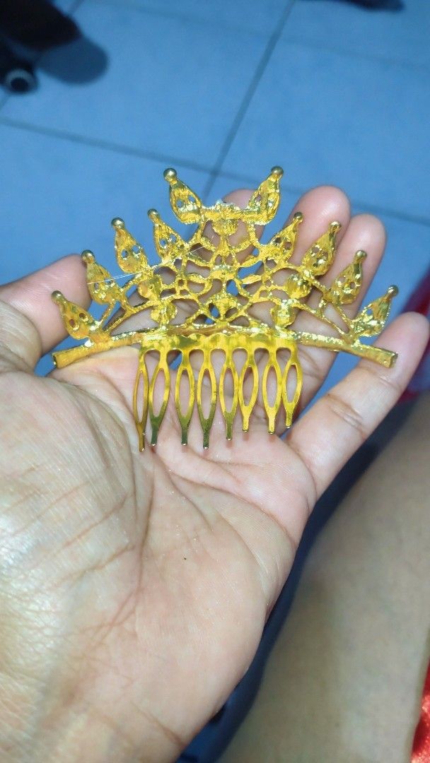 Thai crown gold (Category: Hair Accessories) located in Valenzuela. Submitted by diane.35 (Listing ID 1468102570, Image 2). Description: - Design: Gold tone miniature crown hair comb - Embellishments: Colorful rhinestones in blue, pink, green, orange, and purple - Features: Built-in comb prongs on the back for a secure hold - Styling: Great for updos, ponytails, and half-up hairstyles - Occasions: Fun accessory for parties, costumes, or daily wea