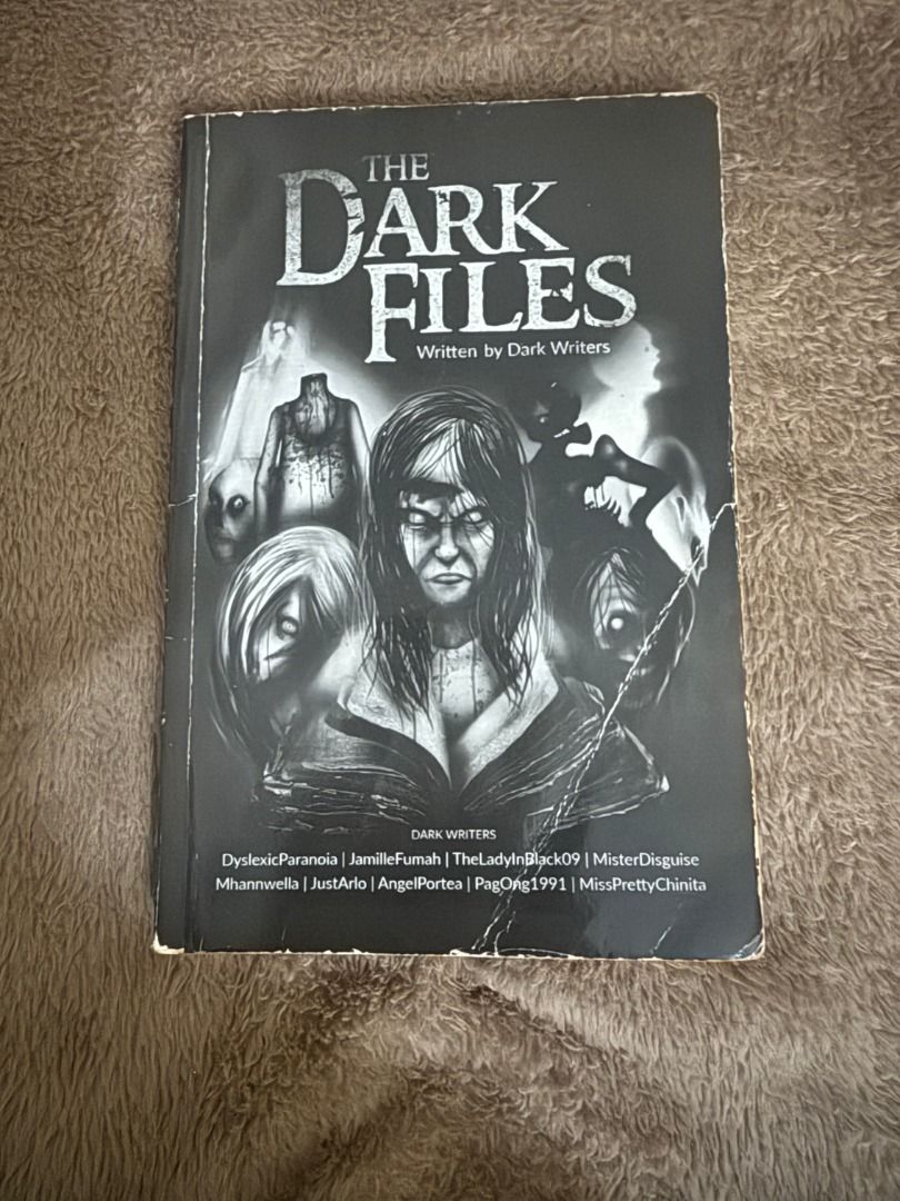 The Dark Files Written by Dark Writers (Category: Storybooks) located in Manila. Submitted by vaultfinds (Listing ID 1468260873, Image 1). Description: Horror anthology book titled The Dark Files. Written by multiple authors including DyslexicParanoia, JamilleFumah, TheLadyInBlack09, and several others listed on the cover. Black and white creepy illustration on the front cover. Softcover format. Spine shows slight wear at the edges from reading a