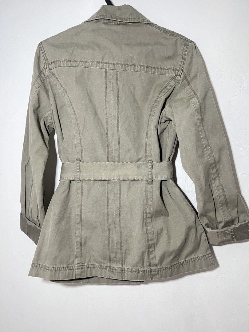 double-breasted belted trench jacket muted olive (Category: Coats, Jackets and Outerwear) located in Quezon City. Submitted by shopkeju (Listing ID 1468090744, Image 3). Description: Style: Short trench coat / trench jacket Color: Olive gray, khaki, or grayish sage green Closure: Double-breasted front with metallic buttons Collar: Wide notched lapel collar Waist: Matching adjustable tie belt Details: Fitted waist, structured seams, flap pockets, 