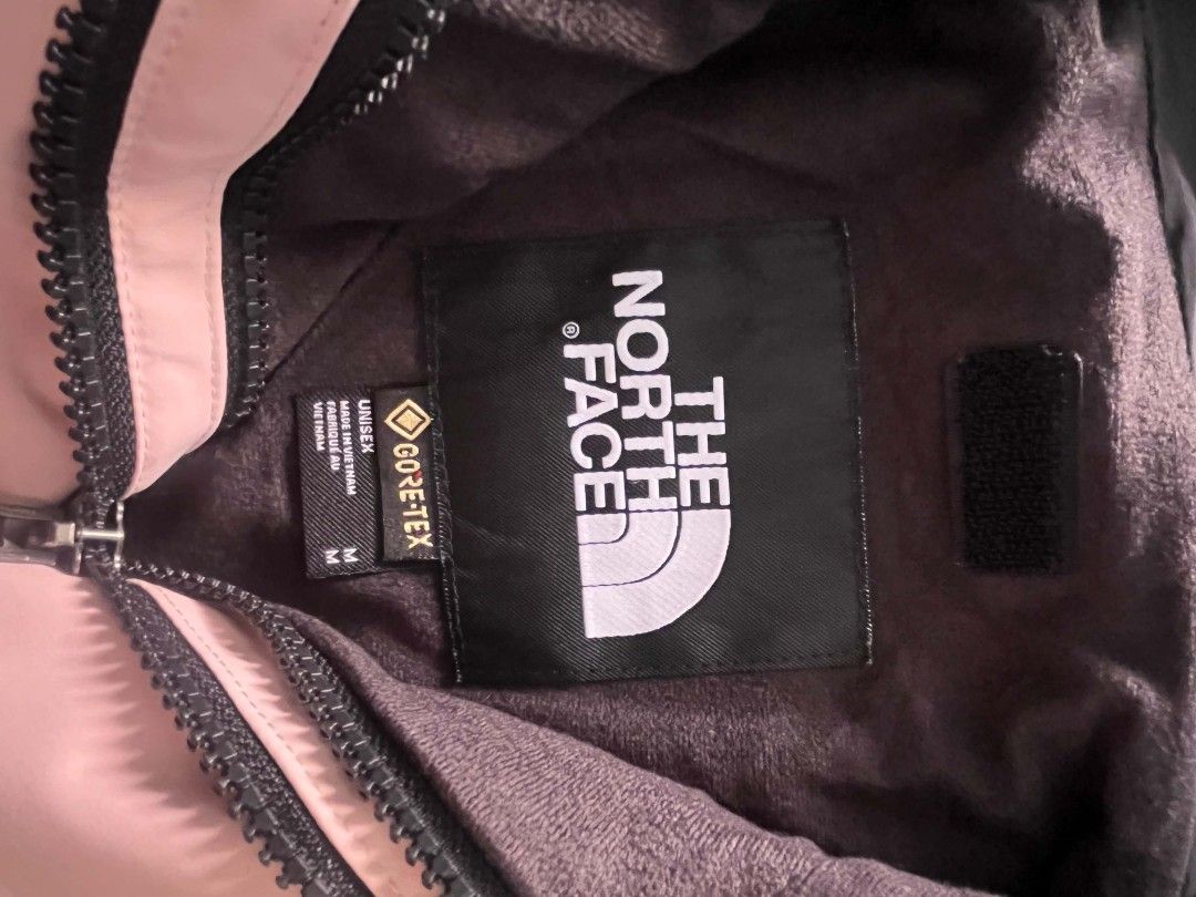 The North Face Pink Black Mountain Jacket (Category: Coats, Jackets and Outerwear) located in Manila. Submitted by necklie_tuballas (Listing ID 1468175373, Image 3). Description: - Brand: The North Face - Colorway: Pink and black with contrasting black cuffs and shoulder panels - Design: Hooded with adjustable drawstrings and snap button front closure - Details: Front chest pocket with bold brand logo printed on the chest - Versatility: Ideal cas